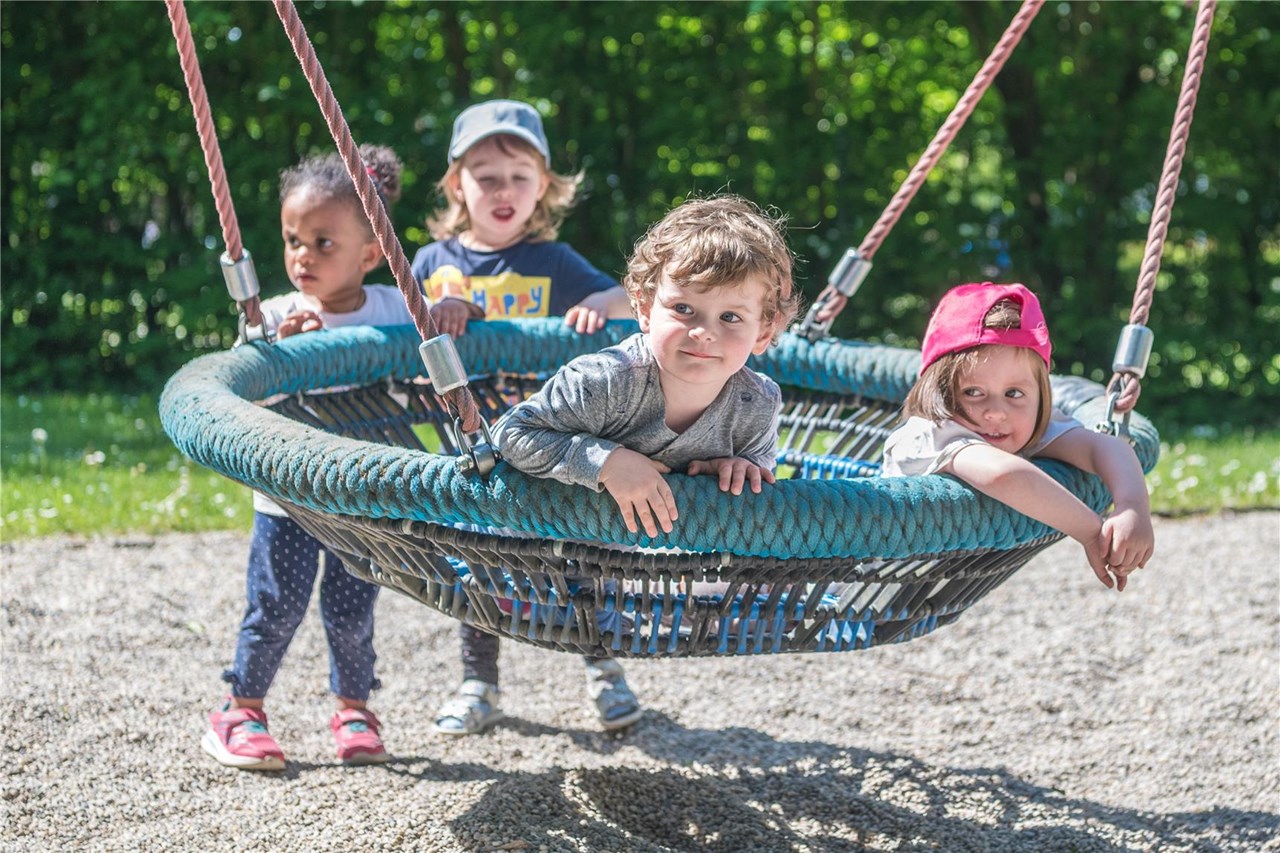 Eine Gruppe von Kindern schwingt fröhlich auf einer Schaukel im Freien.