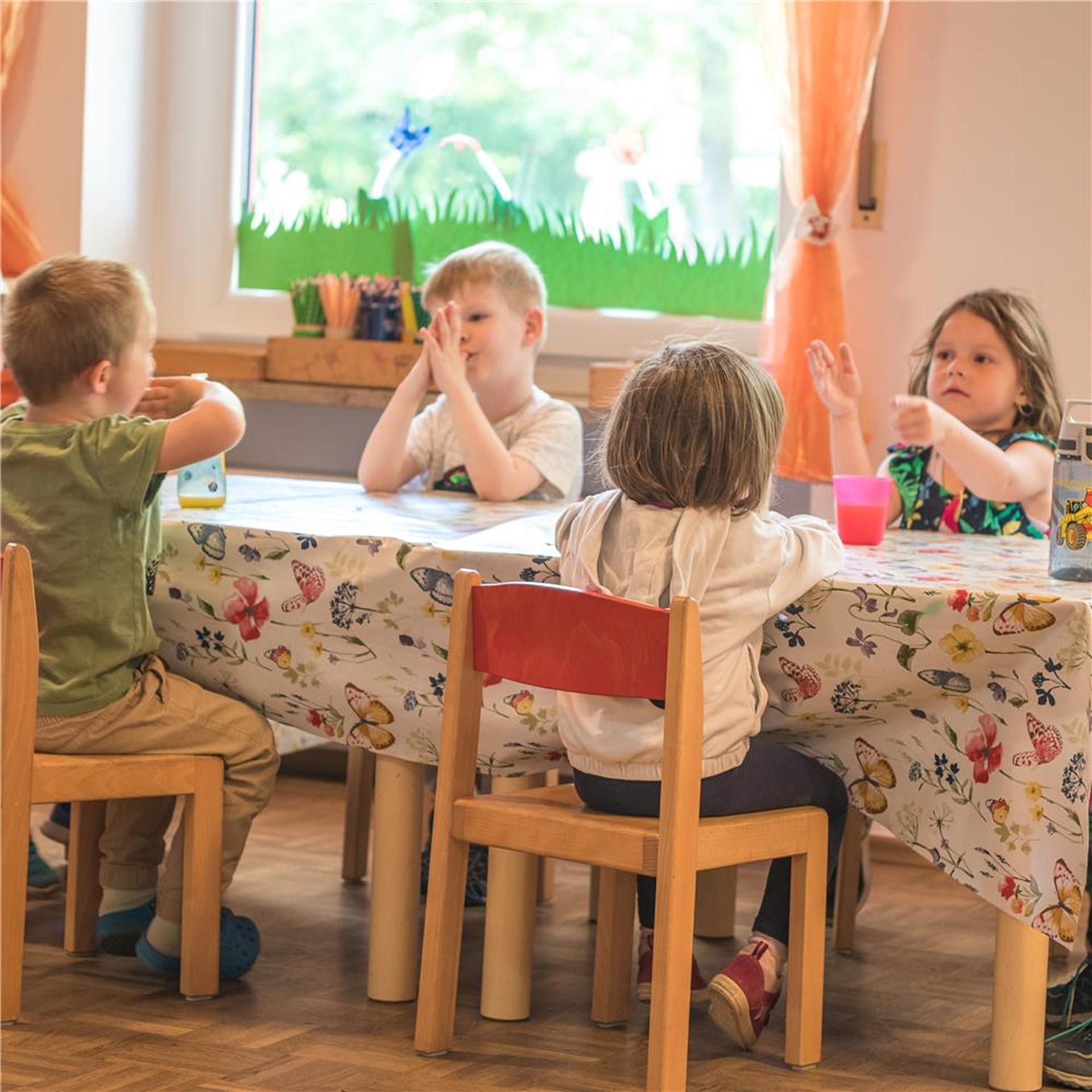 Kinder sitzen an einem Tisch und unterhalten sich fröhlich miteinander.
